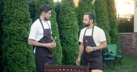 Confident brunette guy with a beard drinks beer with his friend and chats while Stock Footage 283832119