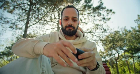 A confident brunette guy with a beard in a white hoodie puts on wireless black Stock Footage 280612361
