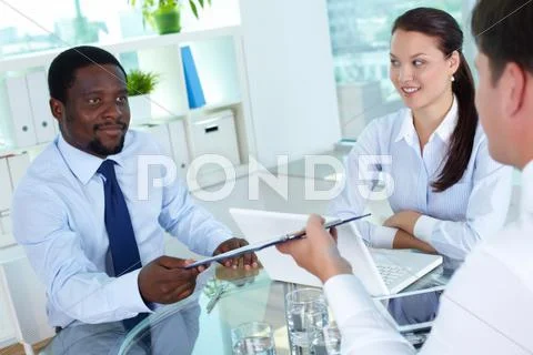 Confident businessman giving contract to his partner in office Stock Photos