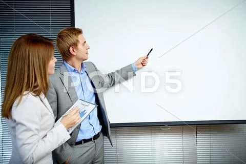 Confident businessman pointing at whiteboard while making speech with smart secr Stock Photos