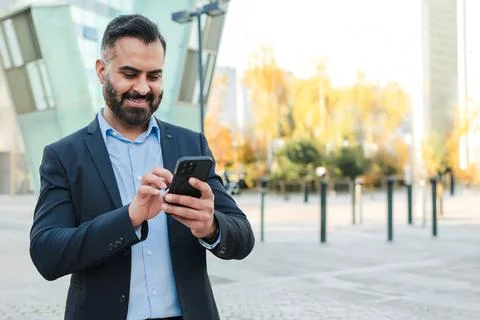Confident businessman smiling while using smartphone to communicate and connect Stock Photos
