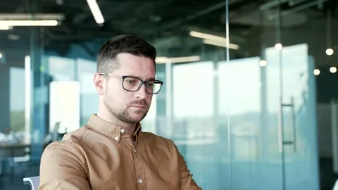 Confident businessman typing on a laptop while sitting at a workplace in busines Stock Footage 254510851