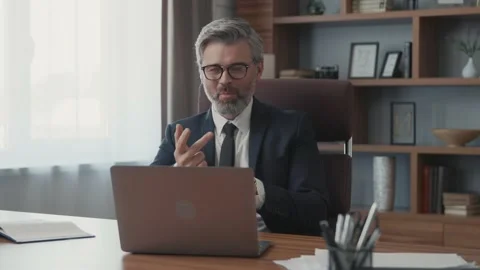 Confident businessman using a laptop talking to a camera making a conference Vídeos de archivo 220189130