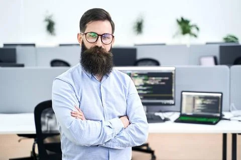 Confident computer programmer developer standing in IT office crossing han... Stock-Fotos