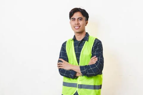 Confident construction worker standing with arms crossed against a clean ba.. Stock Photos