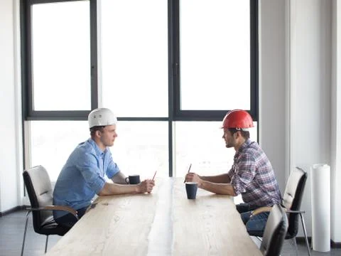 Confident constructors are solving problems while sitting at the table Stock Photos