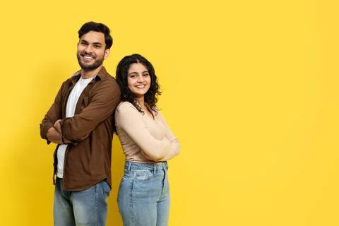 Confident Couple Standing Back to Back on Yellow Background Stock Photos