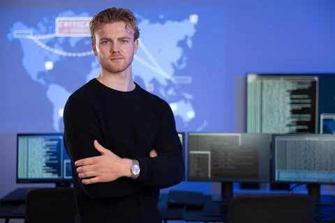 Confident cybersecurity analyst poses in front of data systems with extended Photos