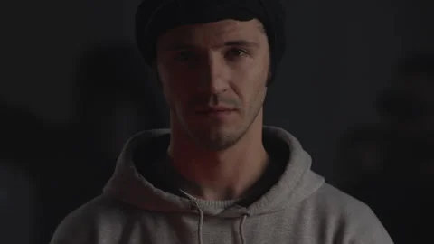 Confident determined young man put black mask and hood on face to hide identity Stock Footage 132108283