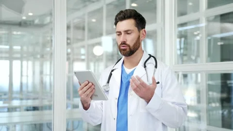 Confident doctor in white coat talking on video call using digital tablet Stock Footage 326897836