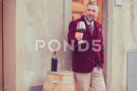 Confident elegant dressed man with glass of red wine standing outdoors Stock Photos
