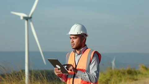 Confident engineer using tablet control wind turbines windmill energy farm. Stock Footage 222886635