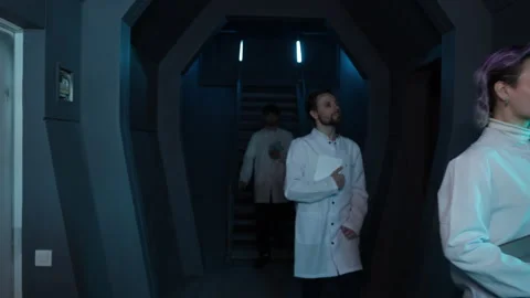 Confident engineers in white uniform in a spaceship interior with bluish Stock Footage 236811054