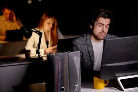 Confident exhausted Capable Manager Working Late Hours in Office. Office is Dark Stock Photos