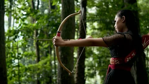 Confident Female Archer Aims Arrow in Lush Forest Wilderness Stock Footage 334792180