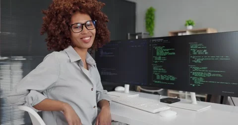 Confident female developer coding at dual monitors in modern office workspace Video stock 338296287