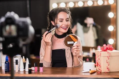 Confident female model using cosmetics in front of camera Stock Photos