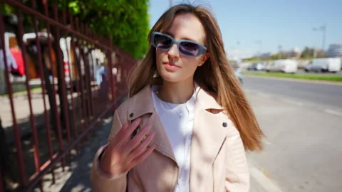Confident female professional striding down city sidewalk, donning pink leather Video stock 308355115