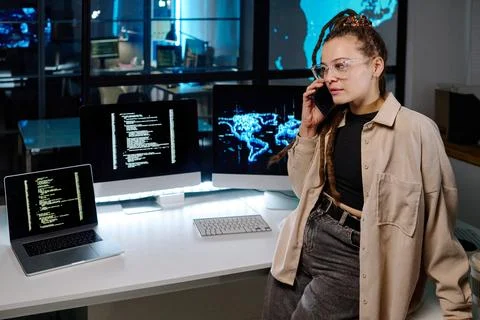 Confident female programmer talking to colleague on smartphone Stock Photos