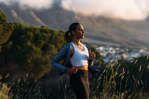Confident female runner practicing outdoors at stunning sunset. Side view ... Stock Photos