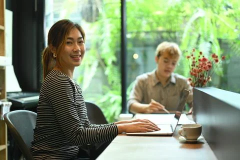 Confident female website developer sitting in modern office with her colleague 스톡 사진