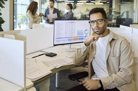 Confident financial analyst portrait at computer with charts dashboard in office Stock Photos