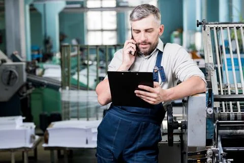 Confident foreman using phone while checking information Fotos de archivo