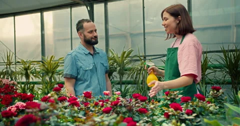 A confident guy with a beard listens from a brunette girl and a greenhouse Stock Footage 280709076