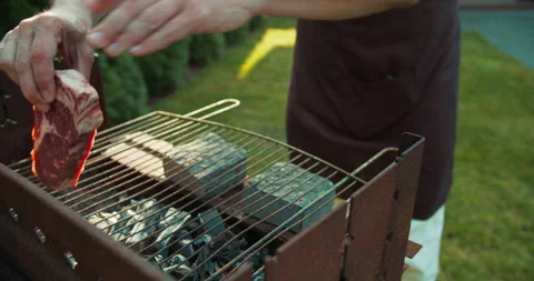 Confident guy in a brown apron takes a premium piece of meat and puts it on a Stock Footage 278715642