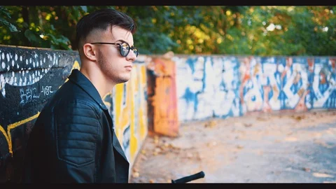 Confident guy is dressed in casual clothes. He is wearing sunglasses with a Video stock 128313675