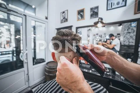 Confident guy sitting at beauty salon . Man haircut. Soft focus. Stock Photos