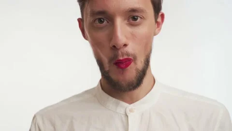 Confident handsome bearded man with makeup look at camera, eat candy close up Stock Footage 147574881