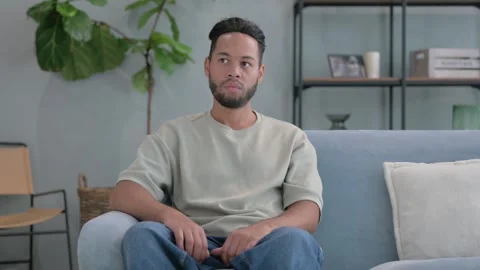 Confident Hispanic Man Sitting on Sofa at Home Vídeo Stock 293256862