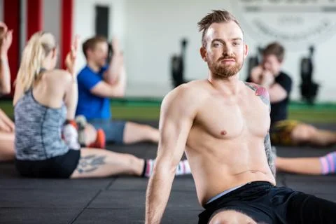Confident Instructor Sitting While Clients Exercising Foto stock