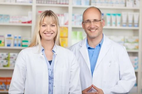 Confident male and female pharmacists standing in pharmacy Stock Photos