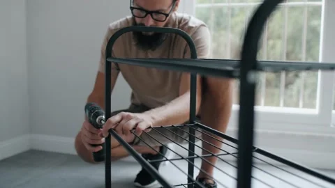 Confident male assembling shelf connect metal plank use cordless screwdriver Stock Footage 233469706