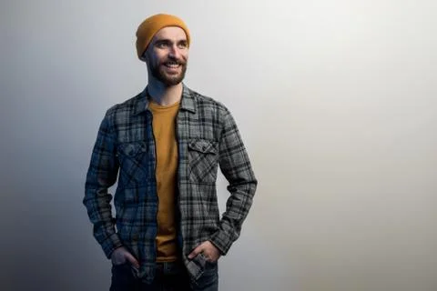 Confident man with a beard dressed in  checkered shirt and yellow hat holds h Stock Photos