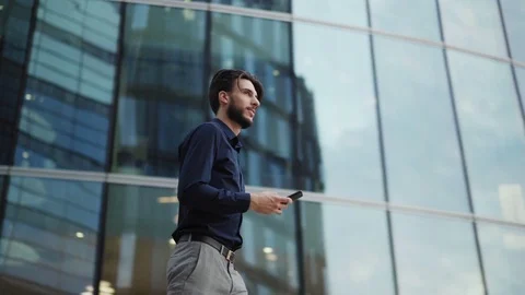 Confident man with cellphone walking down city street Stock Footage 113696438