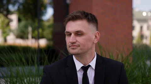 A confident man dressed in a formal black suit and white shirt with a black tie Stock Footage 288011904