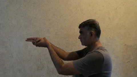 Confident man indoors uses double finger guns to mimic shooting gesture Stock Footage 313279879
