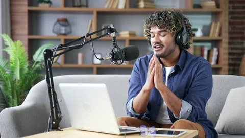 Confident man recording podcast using laptop and microphone sitting in home  Stock Footage 297873425