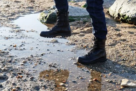 Confident man step into a puddle in black unisex leather boots with laces for Stock Photos