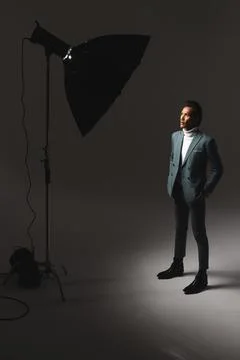 Confident man in stylish suit posing under studio lighting, looking thoughtful Stockfoto's