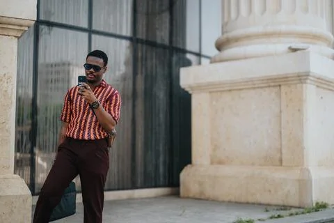 Confident man using smart phone outdoors near modern architecture building Fotos de archivo