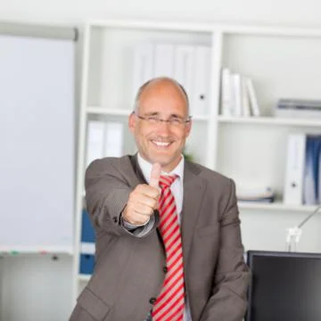 Confident mature businessman gesturing thumbs up Stock Photos