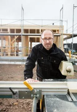 Confident Mature Carpenter Using Table Saw To Cut Plank 写真素材