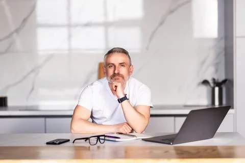 Confident middle aged man using laptop and having video call while working fr Stock Photos