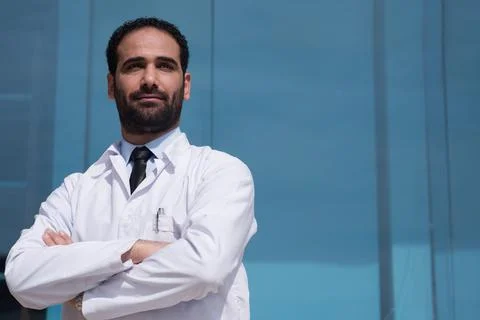 Confident Middle Eastern eye doctor in white coat outside a modern hospital Stock Photos
