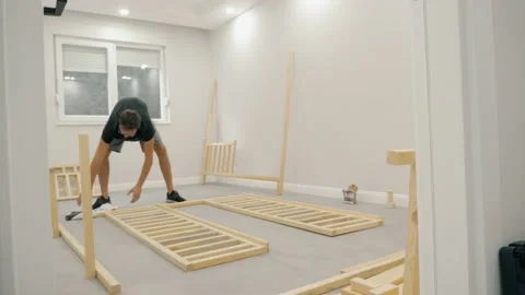 Confident modern man self assembling wooden furniture placing plank on floor use Stock Footage 233469992