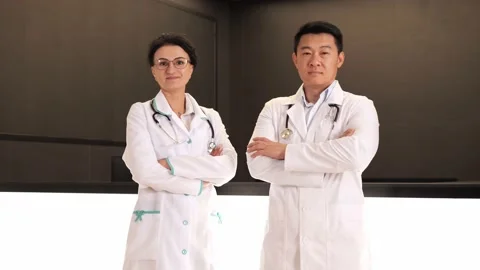 Confident multinational doctors in lab coats posing on camera with crossed arms. Stock Footage 199807000